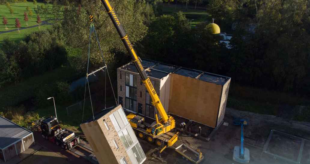 Prefab woning wordt geplaatst met kraanwagen